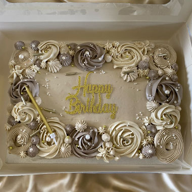 A beautifully decorated birthday cake adorned with creamy swirls in shades of beige and brown, featuring the phrase