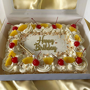 Birthday cake decorated with cherries and pineapple, featuring the words