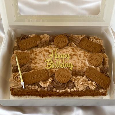 Birthday cake decorated with caramel frosting and topped with Lotus biscuits, featuring a gold