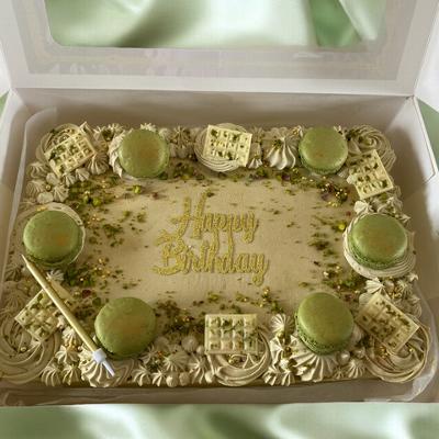 Birthday cake decorated with macarons, cream swirls, and a